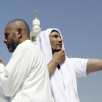 A Muslim pilgrim prays as another takes a photo with his mobile phone at the Grand Mosque on the last day of the annual haj pilgrimage in Mecca